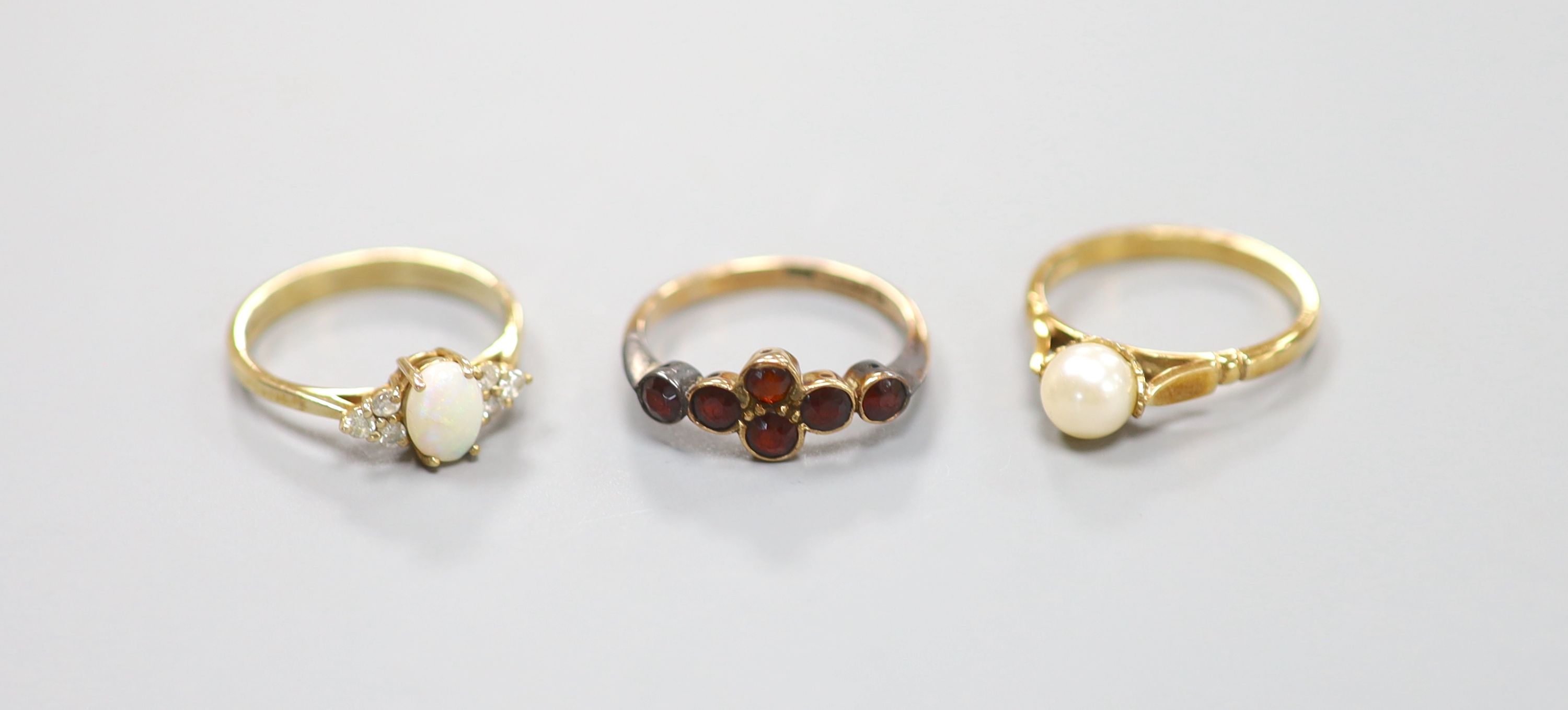 A 9ct yellow gold garnet-set ring, a similar cabochon opal and small diamond ring and a similar pearl-set ring (3) 6.5g